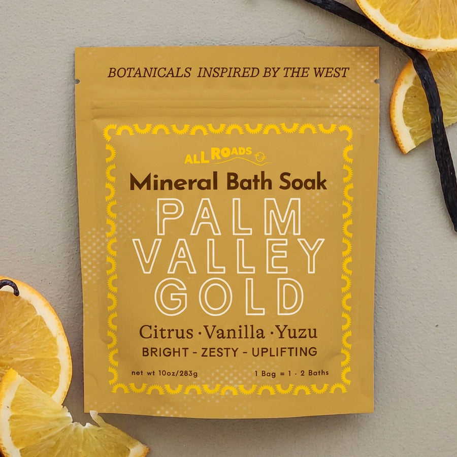 A foil packet of All Roarz Mineral Bath Soak in Palm Valley Gold flavor, styled in a flat lay with citrus slices, vanilla beans, and a neutral background.